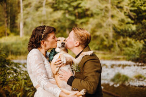 couple kissing at riverfront ceremony area with dog