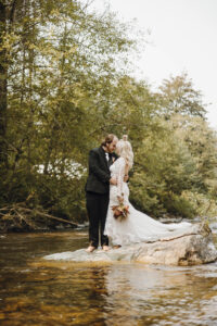Wedding couple portrait near the water's edge on river rocks at Snohomish county waterfront wedding venue River Valley Oasis
