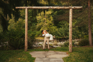 Wide shot of the ceremony site showing the river and tree line woman in man's arms